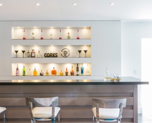 Home bar with built in shelves, wood bar and wood floor.