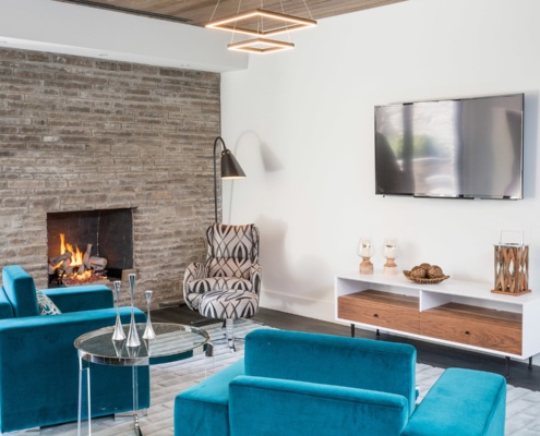Living room with stone firepalce modern chandelier and hardwood floor.