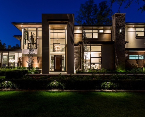 Ultra modern house with wood soffit, stone columns and flat roof.