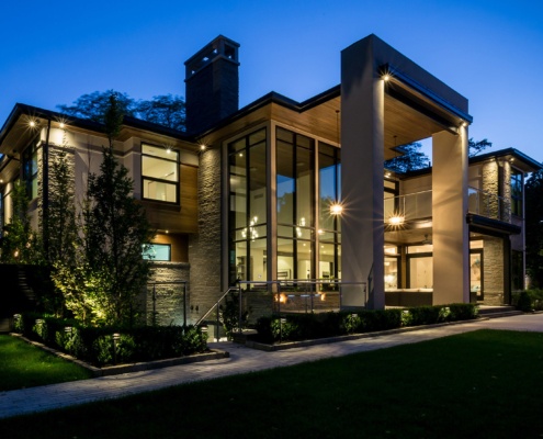 Custom home with basement walkout, natural stone and black frame windows.