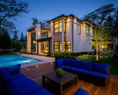 Home exterior with wood deck, inground pool and stone patio.