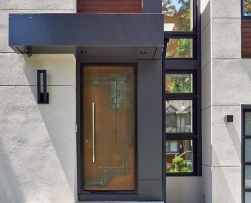 Modern front entry with copper front door, wall sconce and black trim.
