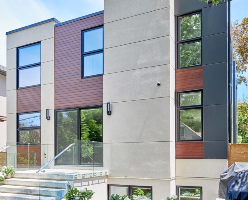 Modern house with wood siding, stucco siding and glass railing.