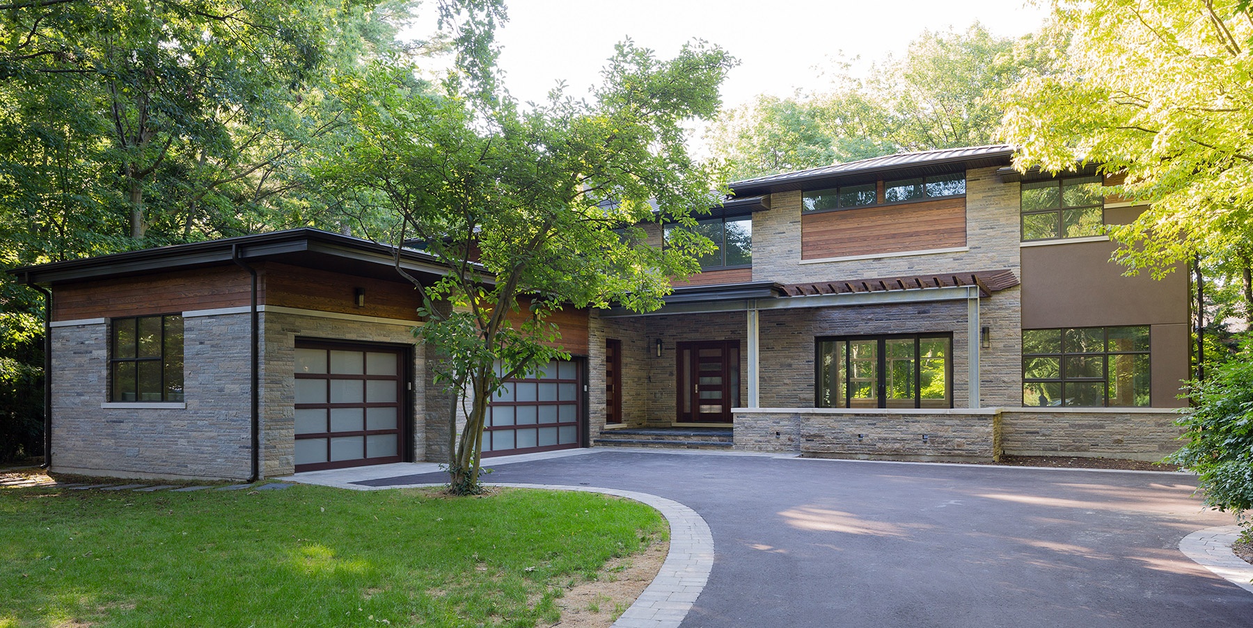 Front exterior of home with stucco siding, natural stone and pergola.