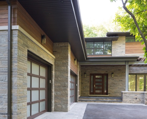 Mississauga renovation exterior with wood soffit, stone column and sconce lighting.