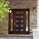 Modern front entry with wood front door, stone steps and horizontal stone wall.