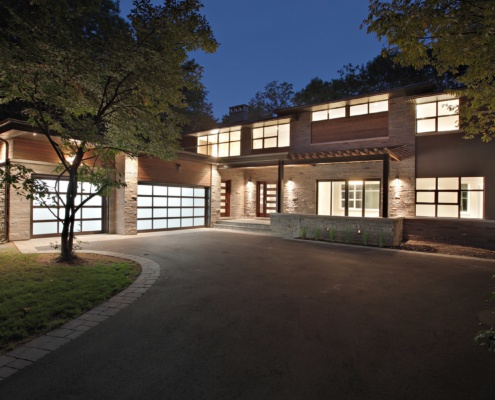 Renovation front elevation with wood siding, natural stone and black frame windows.