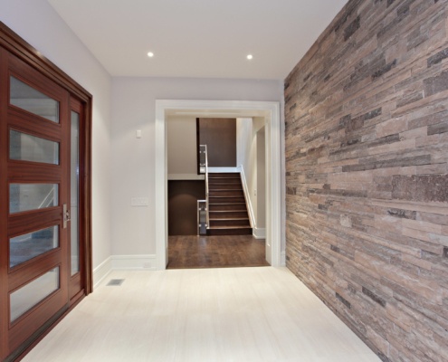 Home front entry with wood front door, stone wall and tile floor.