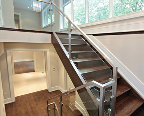 Modern staircase with glass railing, white baseboard and white frame windows.
