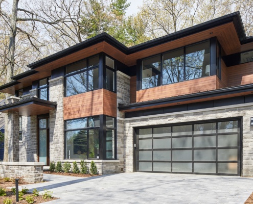 Modern custom home with natural stone, wood siding and frost glass garage door.