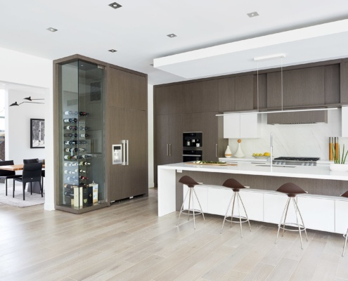 Modern kitchen with white cabinets, large island and wine storage.