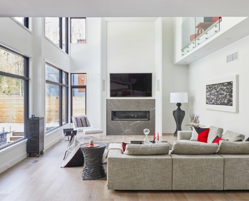 Modern family room with hardwood floor, stone fireplace and large windows.