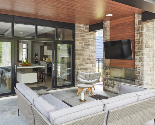 Backyard patio with stone fireplace, black frame window and wood soffit.