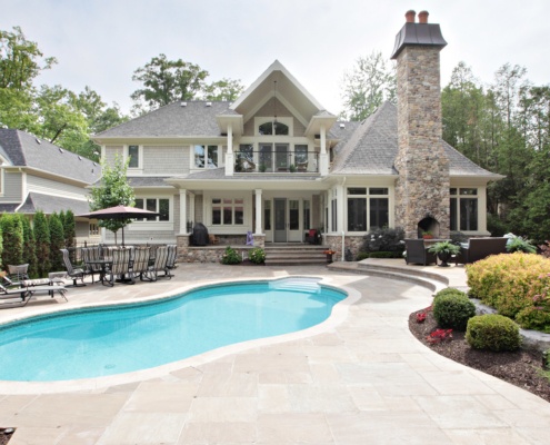 House exterior with stone patio, inground pool and stone siding.