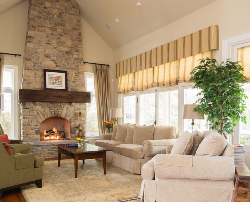 Living room with white frame windows, french doors and stone fireplace.