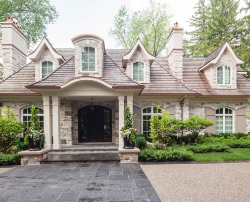 Stone house with gabled roof and covered entry.