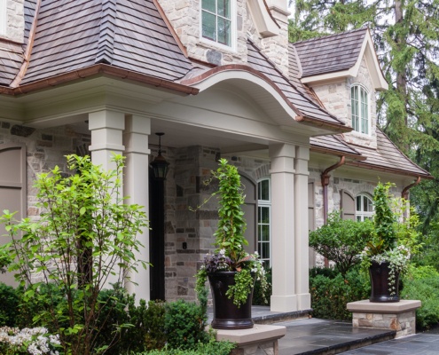 Home front entry with stucco columns, shutters and flagstone walkway.