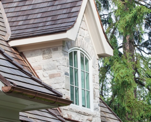 Oakville home with stone gable, wood shingles and copper detailing.