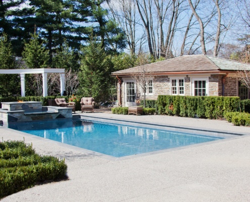Concrete patio with inground pool and stone guest house.