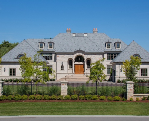 Chateau style home with cut stone, stucco siding and wood front door.