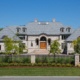 Chateau style home with cut stone, stucco siding and wood front door.
