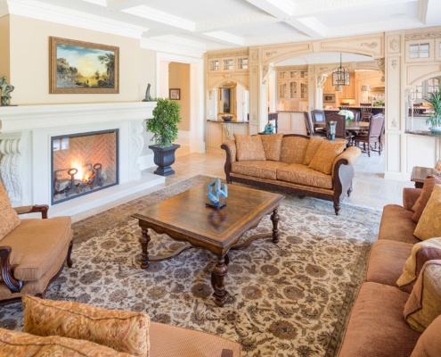 Formal living room with stone fireplace, wood furniture and white trim.