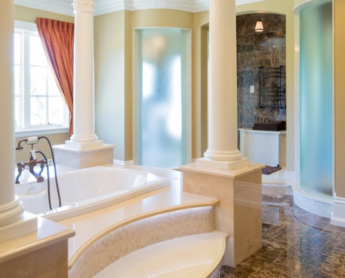Master bathroom with tile floor, columns and white frame windows.