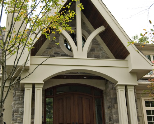 Home entry with wood soffit, white columns and wood front doors.