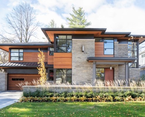 Natural modern home with floating roof, sconce lighting and stone columns.