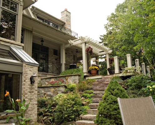 Backyard garden with stone steps, pergola and stucco columns.