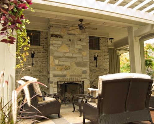 Outdoor sitting room with stone fireplace, wood ceiling and wood floor.