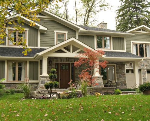 House renovation with stone siding, covered porch and shingled roof.