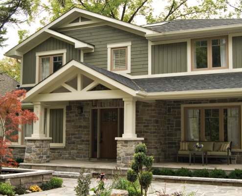 Custom home with horizontall siding, stone columns and white trim.