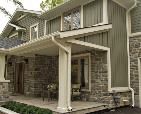 Traditional home design with stone, wood siding and covered front porch.