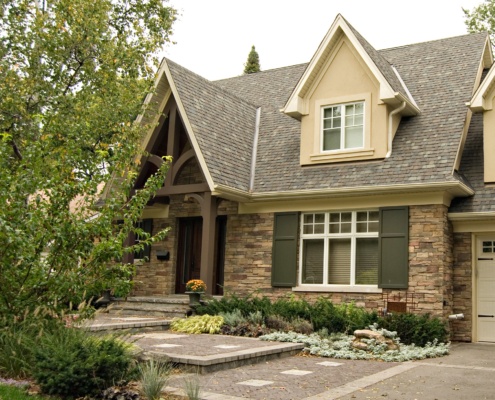 Traditional home with stone siding, covered entry and wood front door.