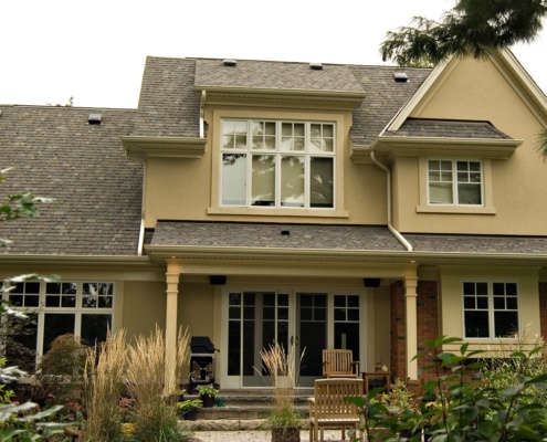 Two storey house with large windows, stucco and gabled roof.