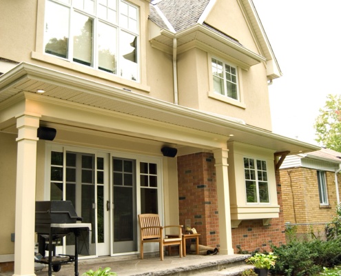 Rear elevation with covered porch, stucco columns and white trim.