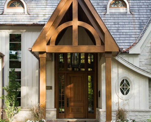 Traditional style house with oval winodw, stone siding and wood front door.