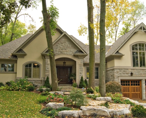 Traditional house upgrade with wood garage door, arched window and stone siding.