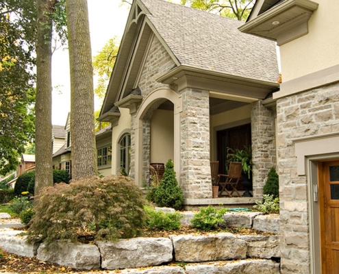 Renovation with natural stone, stone retaining wall and wood garage door.