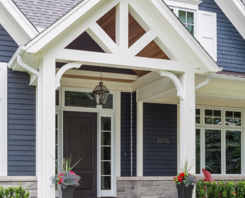 Custom home with white portico, white trim and wood door.