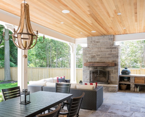 Stone deck with stone fireplace, wood chandelier and wood ceiling.