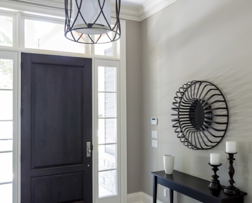 Front foyer with wood door, tile floor and white baseboard.