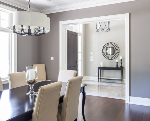 Sophisticated dining room with white baseboard, hardwood floor and wood table.
