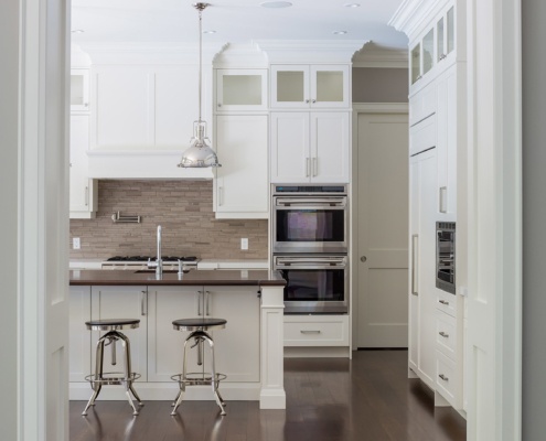 Custom home with white cabinets, stainless steel appliances and double oven.
