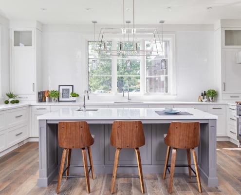 Traditional kitchen with white drawers, gray island and modern chandelier..