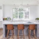Traditional kitchen with white drawers, gray island and modern chandelier..