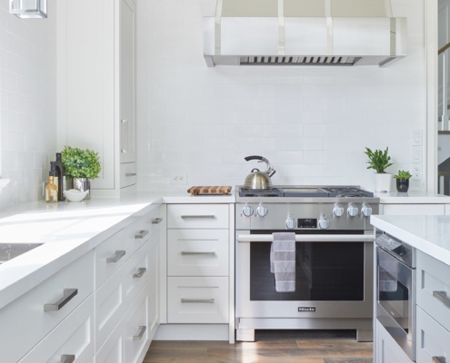 Traditional kitchen with white backsplash, white cabinetry and white countertops.