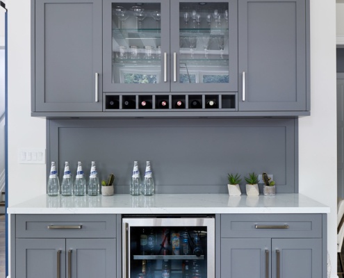 Kitchenette with white countertop, minifridge and gray cabinets.