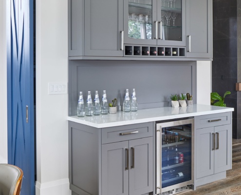 Servery with gray cabinets, white baseboard and glass cabinets.